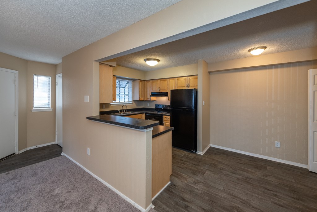 A kitchen with a black refrigerator and wooden cabinets.
