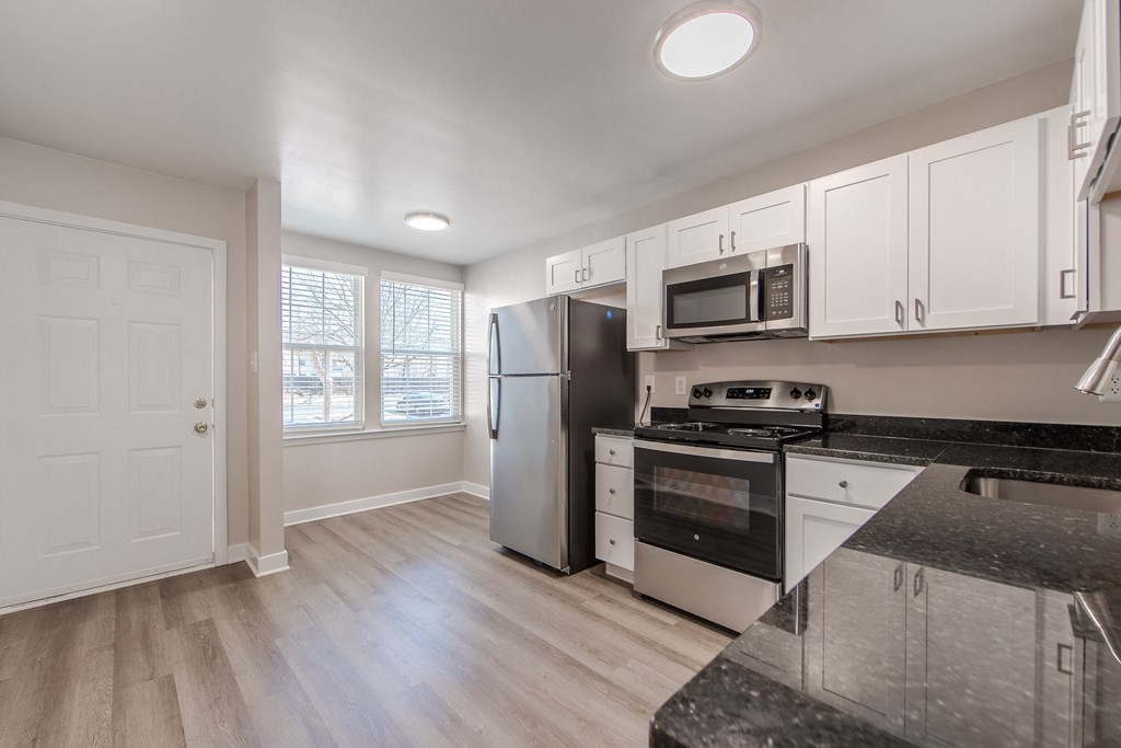 A kitchen with white cabinets and a black countertop.