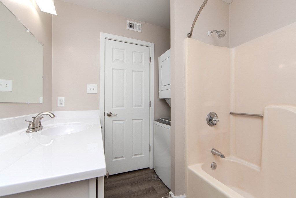 A white sink with a silver faucet is on a white countertop in a bathroom.