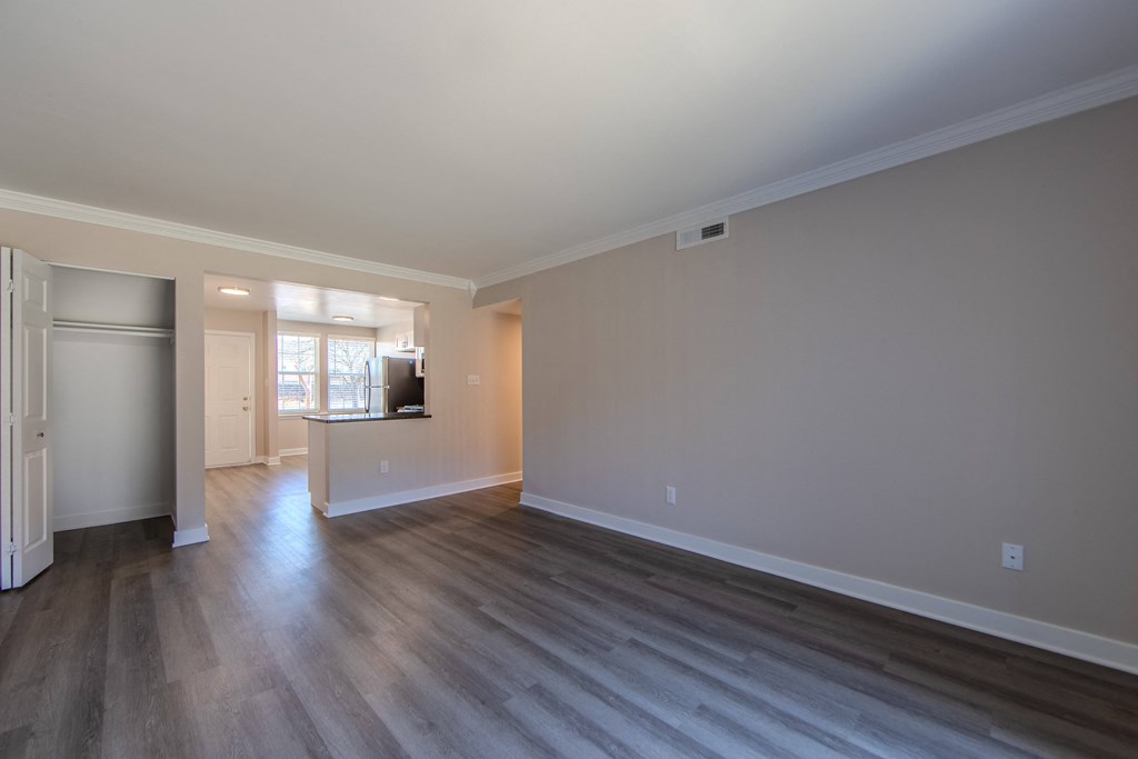 A large empty room with wooden floors and a door on the left.