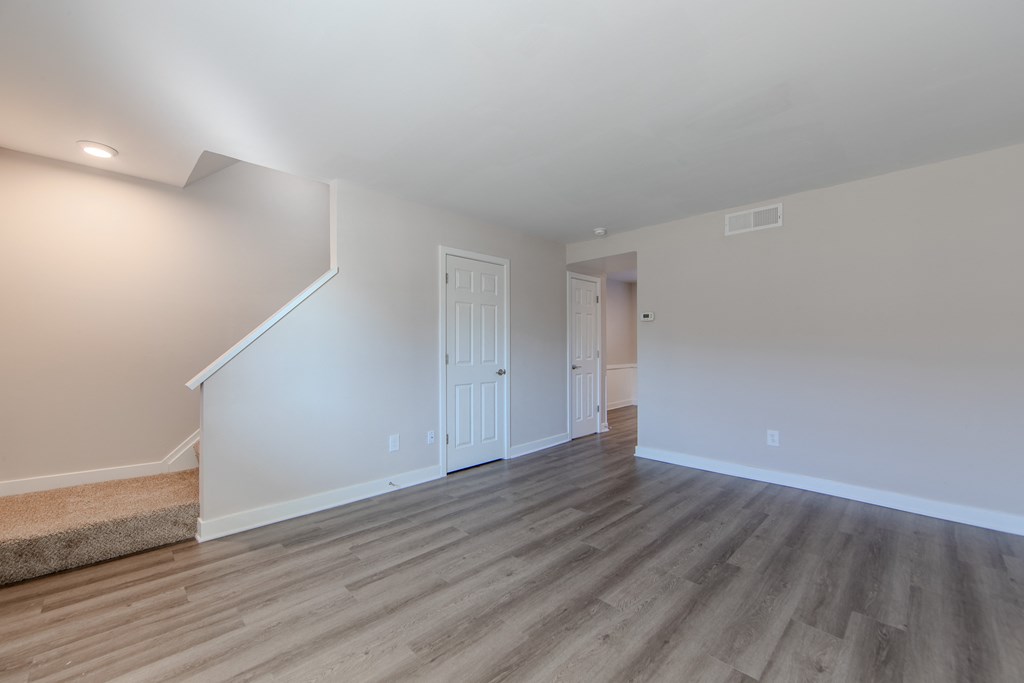 A room with wooden flooring and white walls.