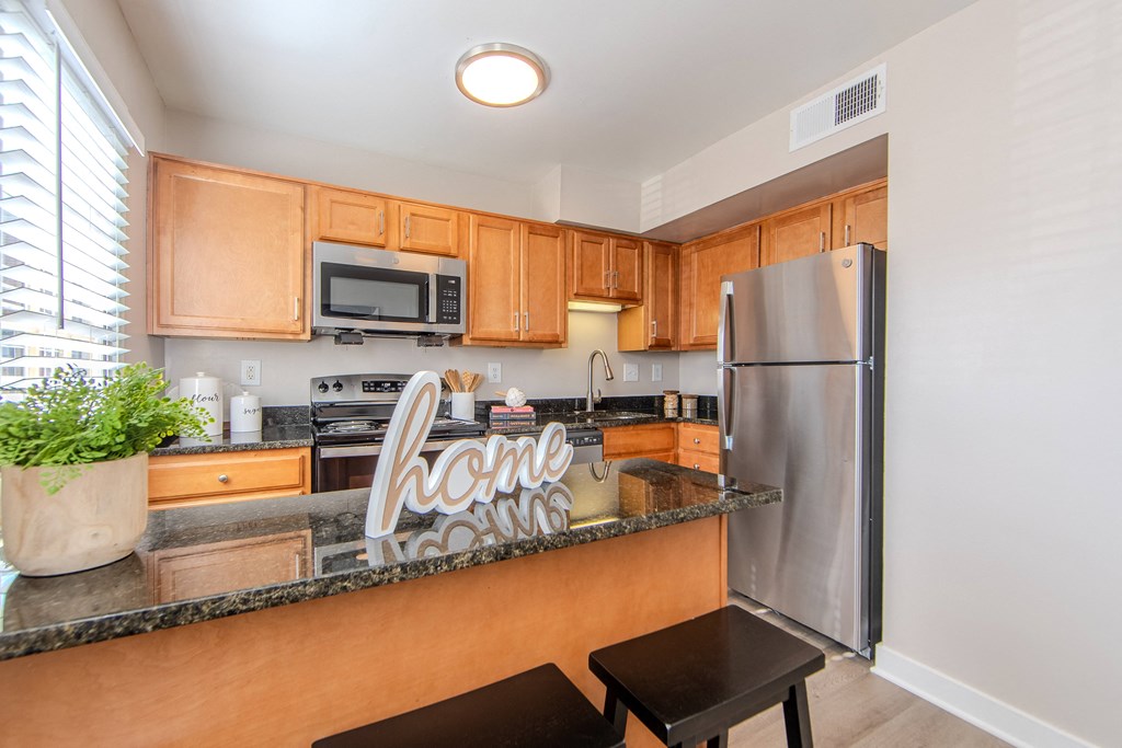 A kitchen with wooden cabinets and a black refrigerator.