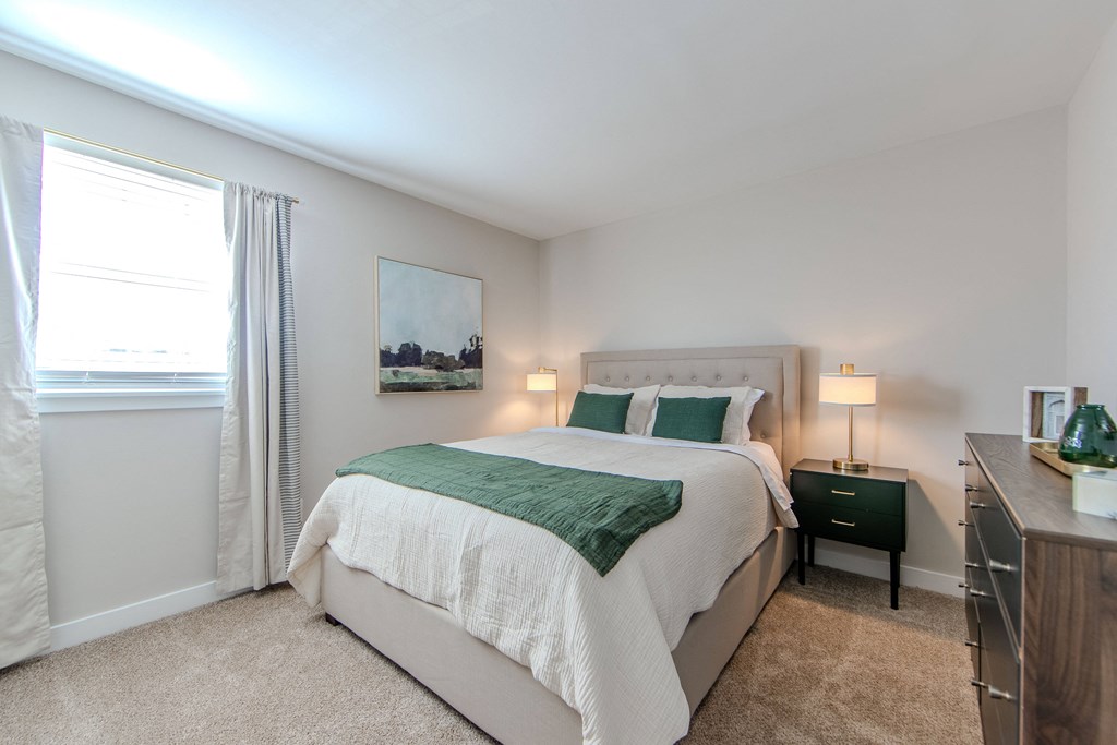 A bedroom with a large bed and a painting on the wall.