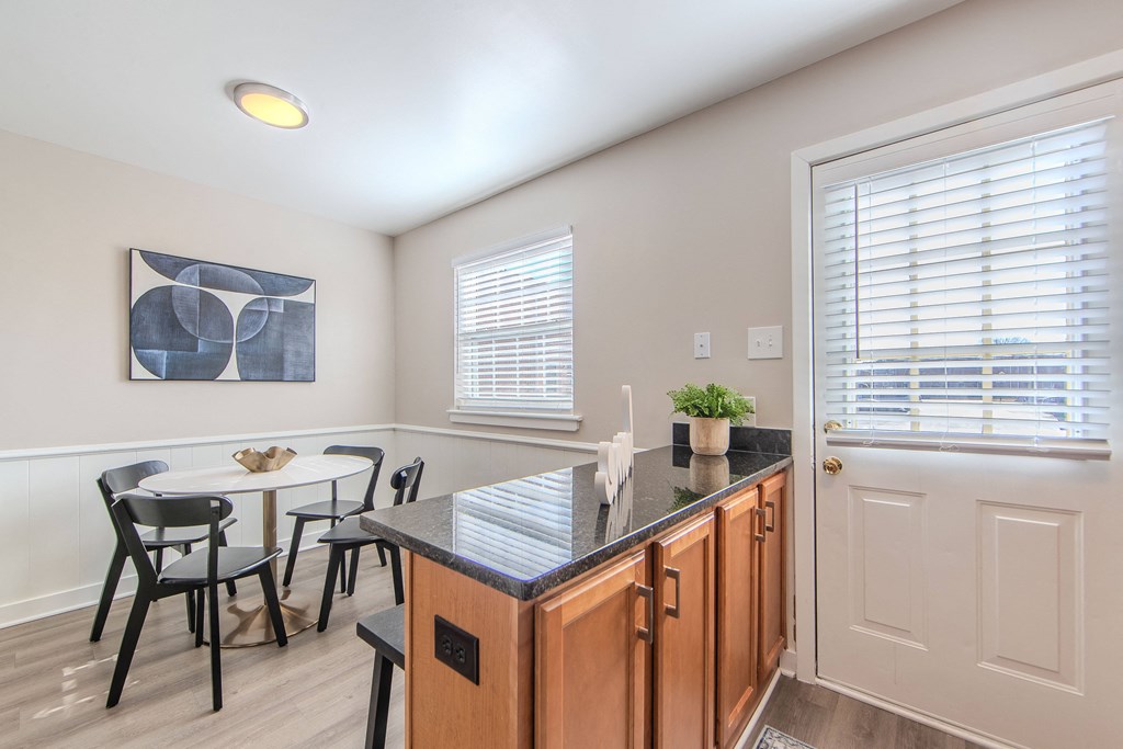 A kitchen with a table and chairs and a plant on the counter.