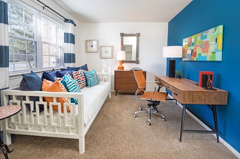 a bedroom with a bed and a desk and a window