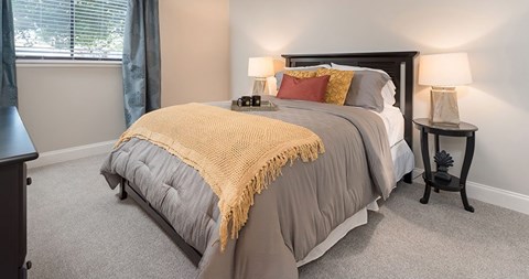 A bedroom with a bed covered in a grey and yellow comforter.