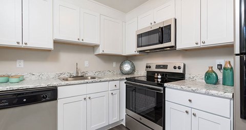 A kitchen with white cabinets and black appliances.