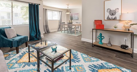 A living room with a glass coffee table and a blue chair.