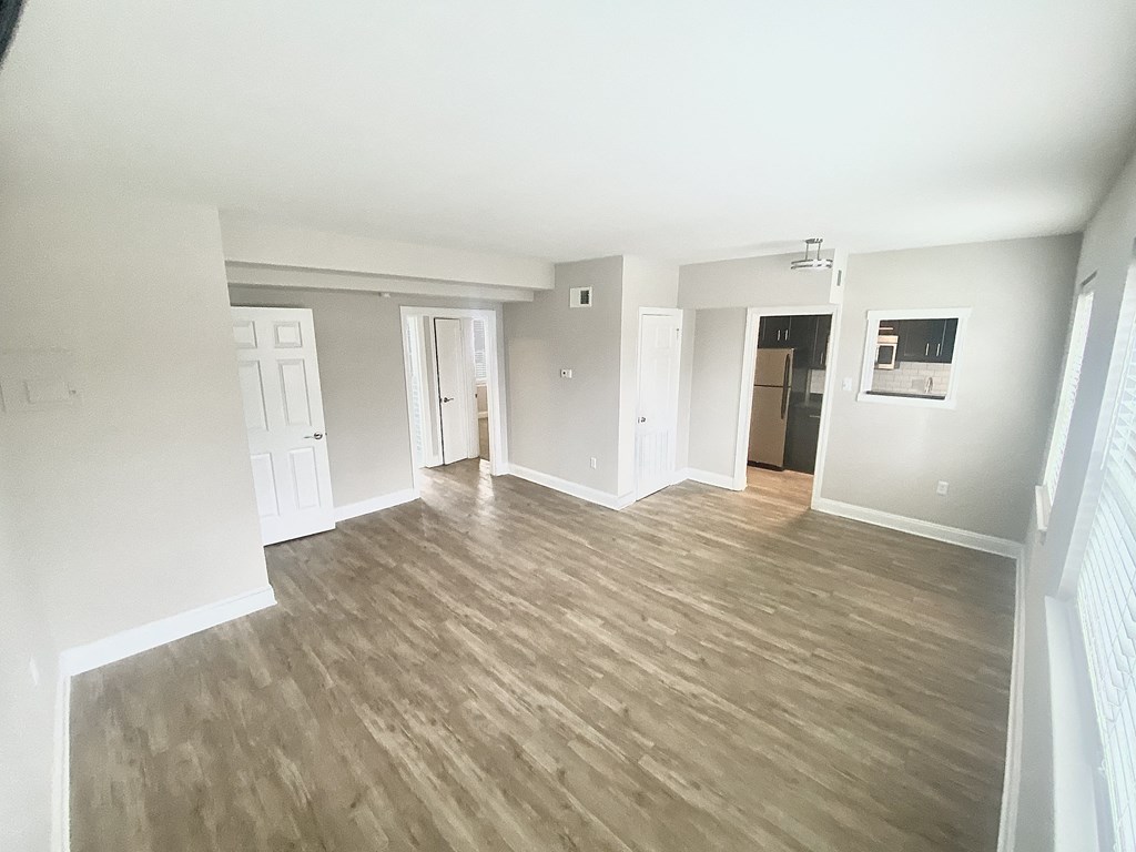 an empty living room with wooden floors and white walls