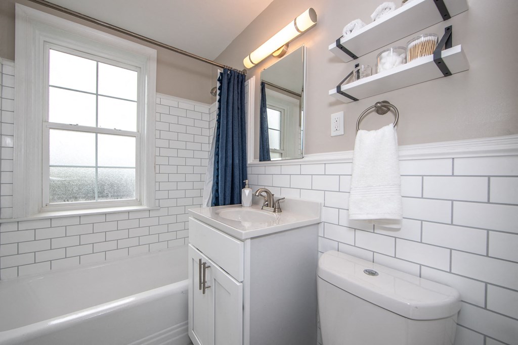 a white bathroom with a window and a sink and a toilet