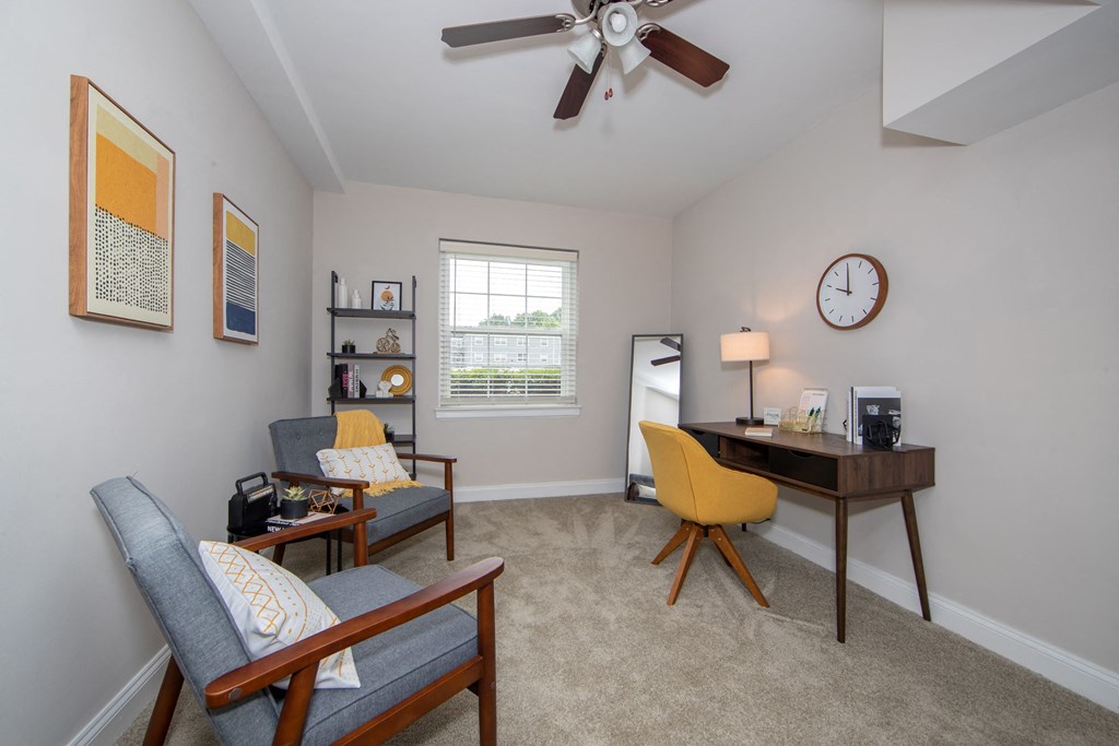 a living room with a ceiling fan and a desk with a chair