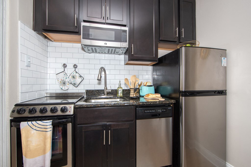 a small kitchen with stainless steel appliances and black cabinets