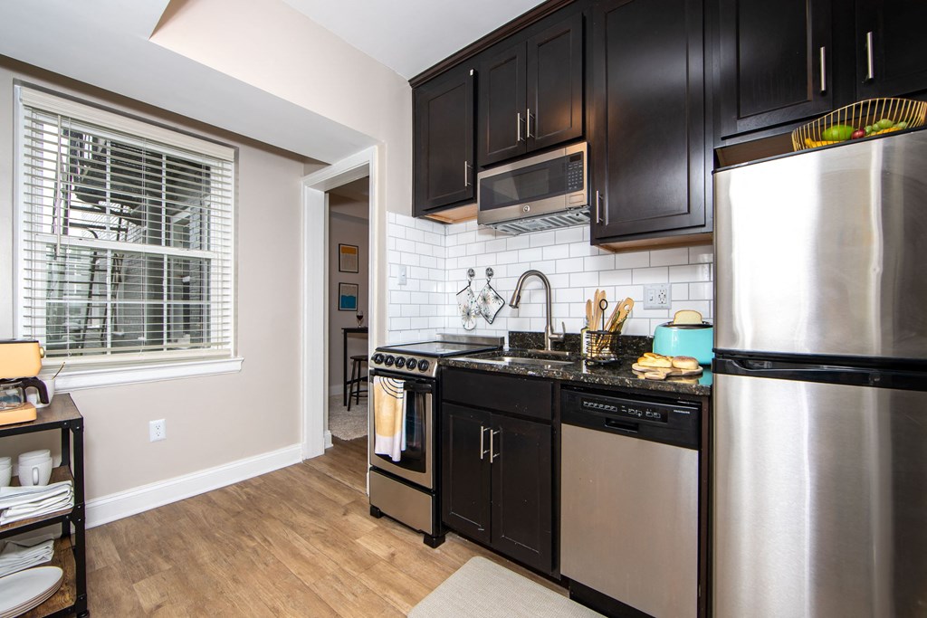 a kitchen with black cabinets and stainless steel appliances and a window