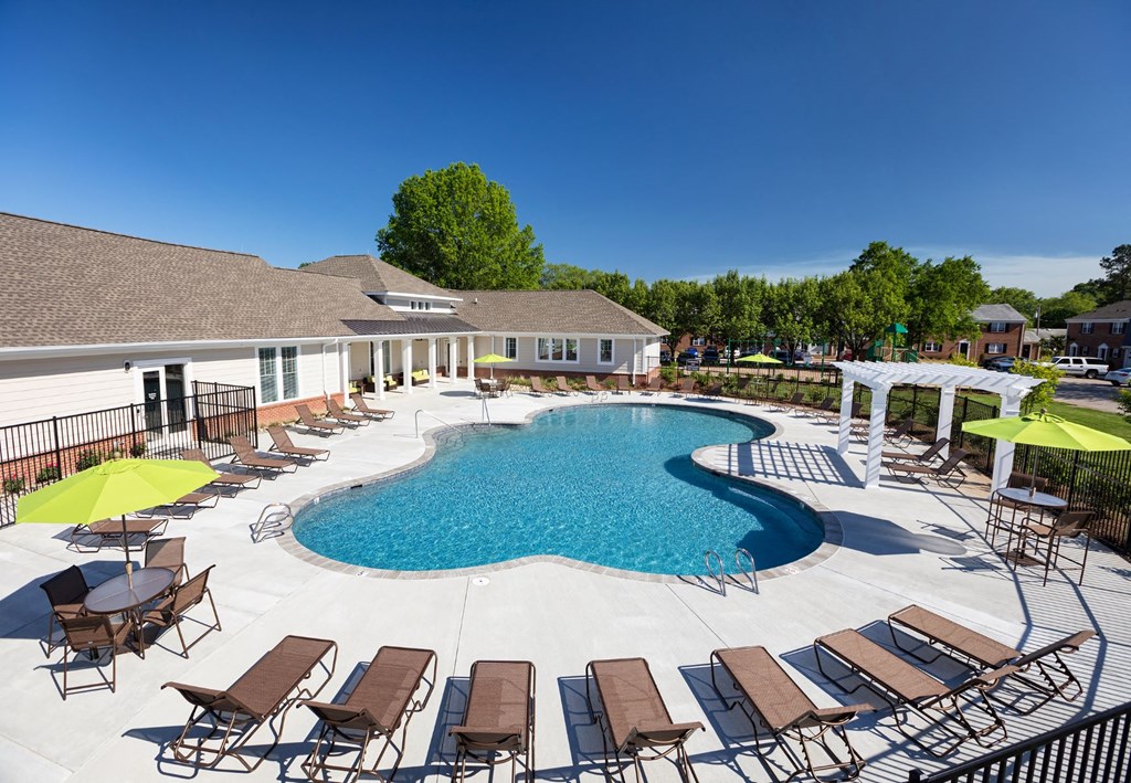 our resort style swimming pool is surrounded by lounge chairs and umbrellas