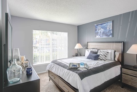 A bedroom with a large bed and a window with blinds.