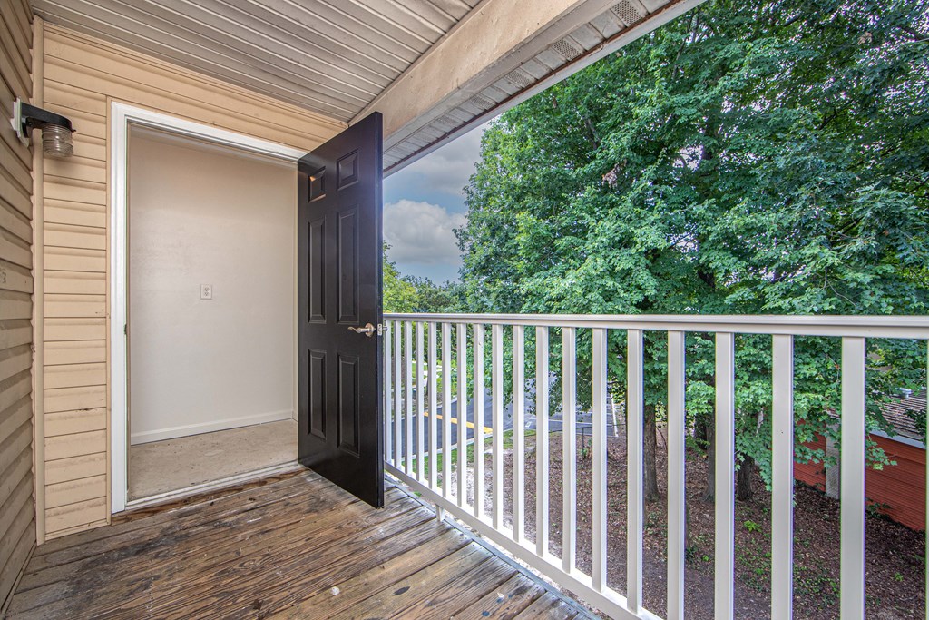 an open door leading to a balcony with trees in the background