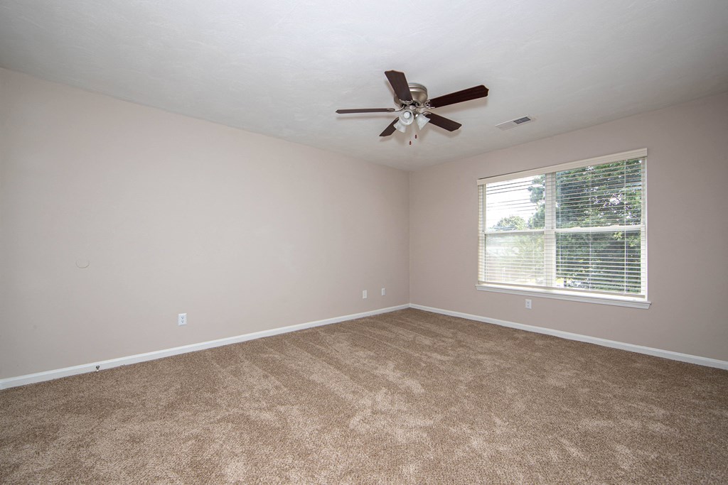 an empty room with a ceiling fan and a window