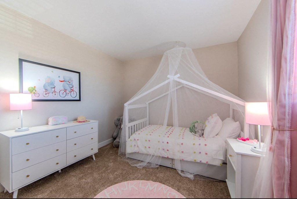 A baby's room with a white crib and a white dresser with a pink blanket on top.