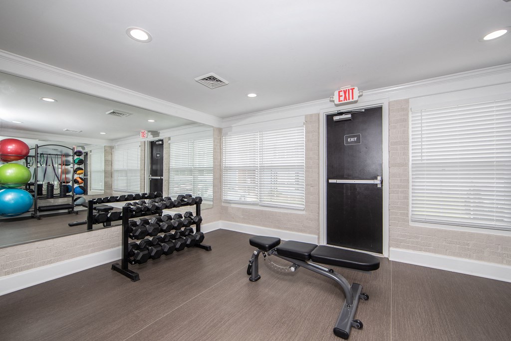 A gym with a variety of equipment including a bench, weights, and a mirror.