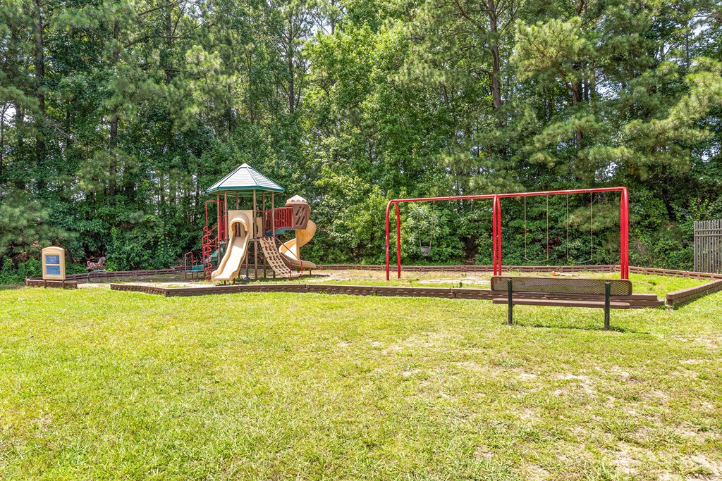 A playground with a red swing set and a green canopy.