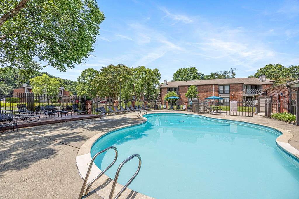 A large swimming pool surrounded by trees and a fence.