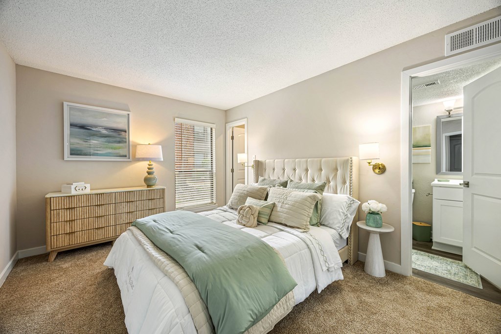 A bedroom with a bed, nightstand, and a painting on the wall.