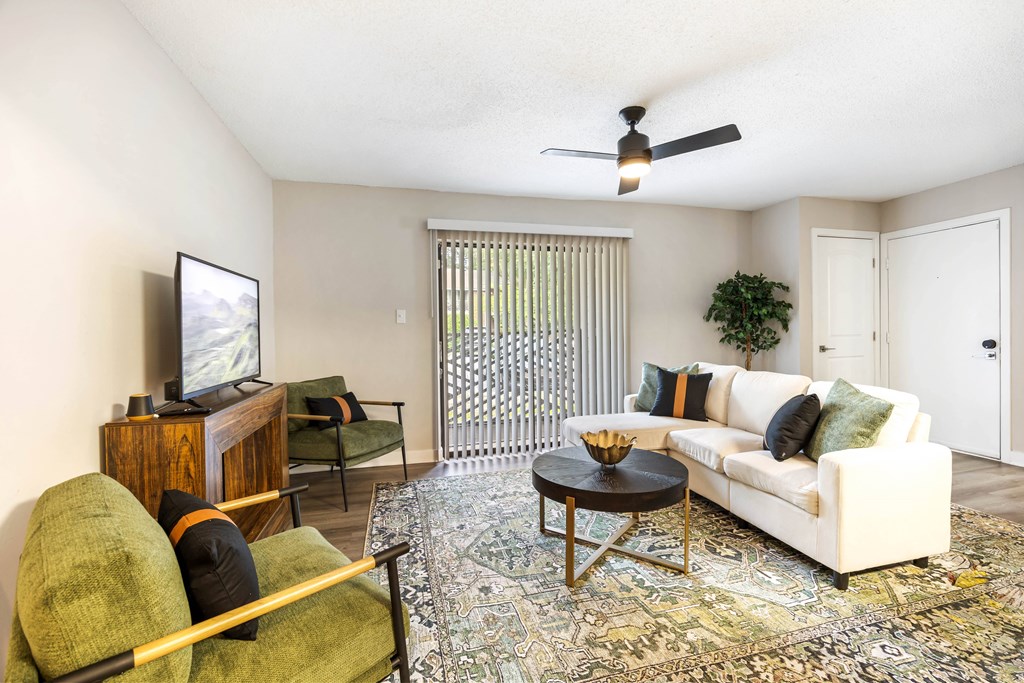 A living room with a white couch, a green chair, and a wooden cabinet.