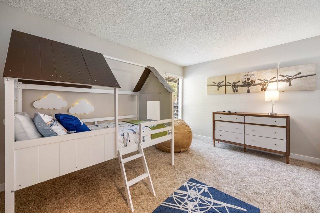 A room with a bunk bed and a dresser.