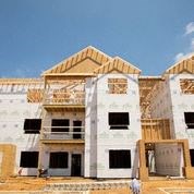 A house under construction with white walls and wooden beams.