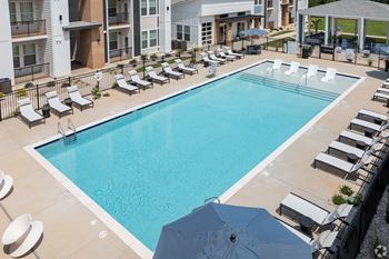 a swimming pool with lounge chairs and umbrellas in front of a building