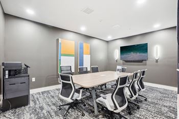 a conference room with a table and chairs and a television