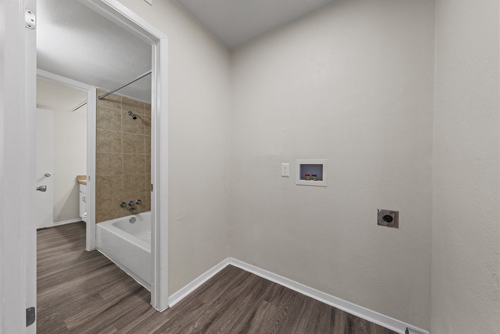 a bathroom with a tub and a shower in a room with wooden floors at Parks on the Green, Temple, Texas