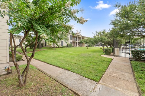 Manicured lawn with walkway and pool gate at Parks on the Green Apartments, Temple, 76504