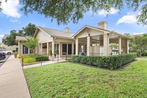 Clubhouse building with covered porch and landscaping at Parks on the Green Apartments, Texas