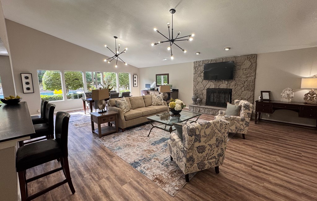 A living room with a stone fireplace and a large window.