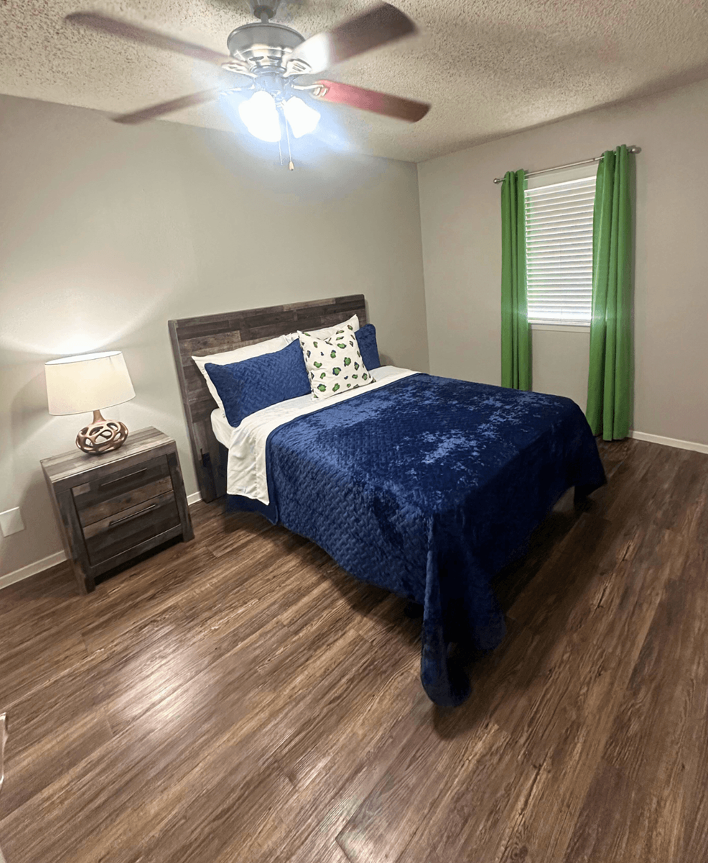 A bedroom with a bed, nightstand, and a ceiling fan.
