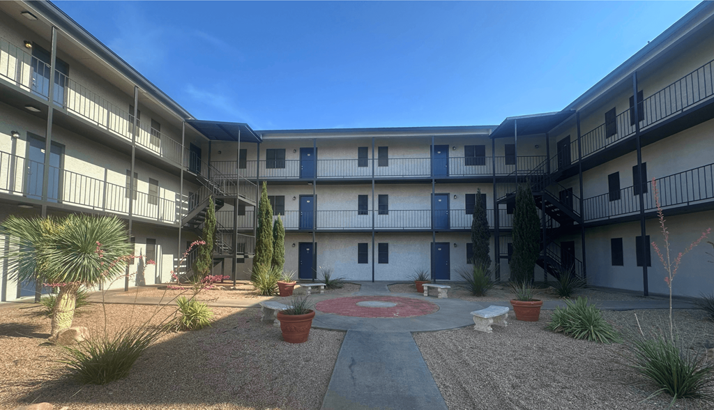 A courtyard with a red circle in the middle and plants around.