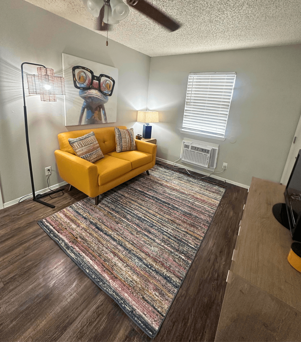A living room with a yellow couch and a rug.