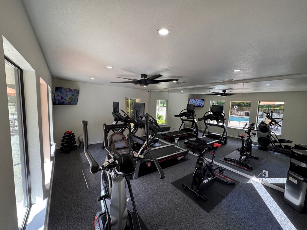 A gym with a row of exercise bikes and a television.
