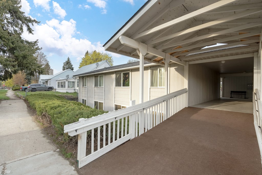 a white porch with a white railing in front of a white house