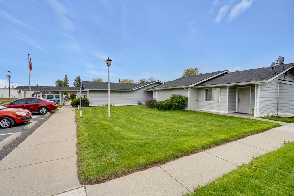 a white house with a lawn in front of a parking lot