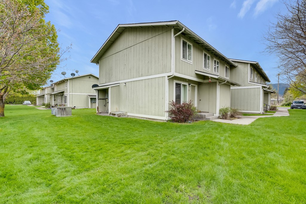 a row of houses with green grass and a sidewalk
