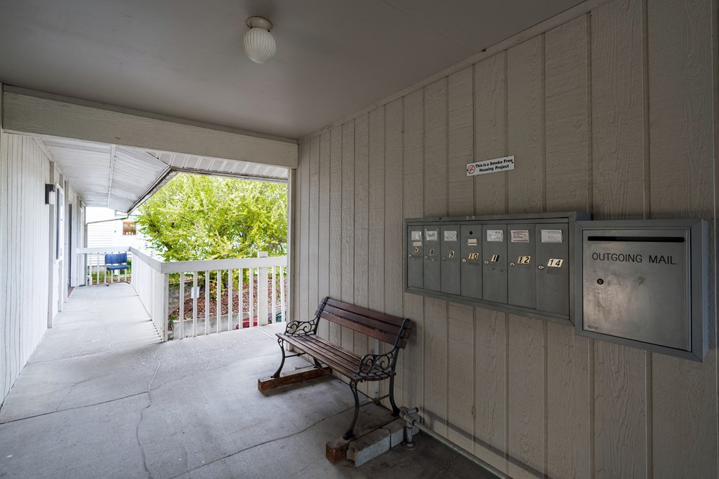a bench on a porch in front of a mail box