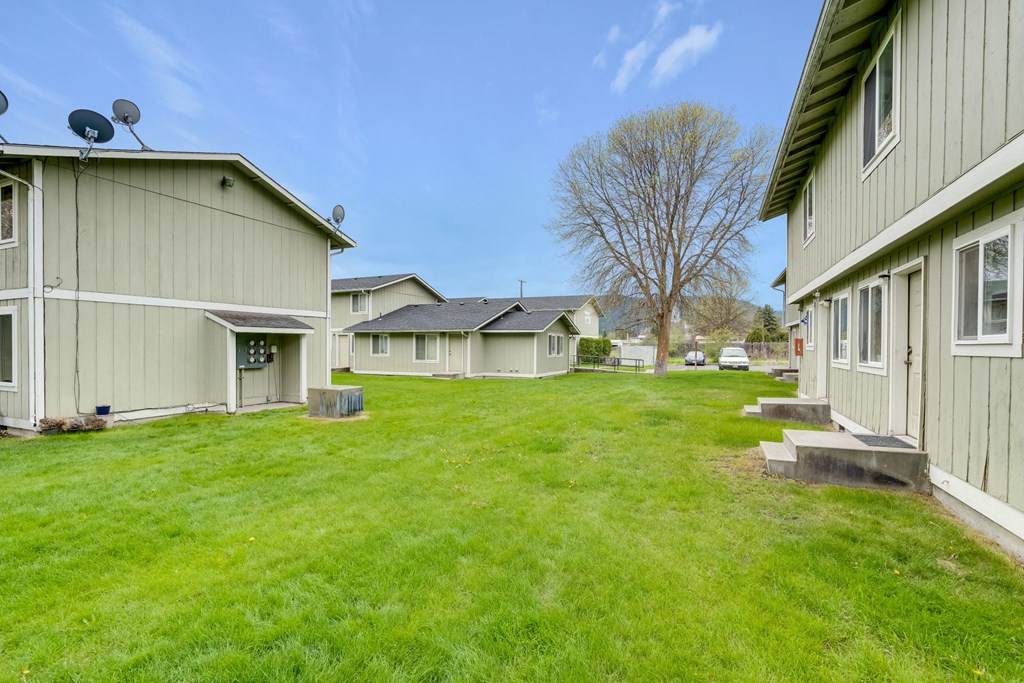 a row of houses with a green lawn and a blue sky