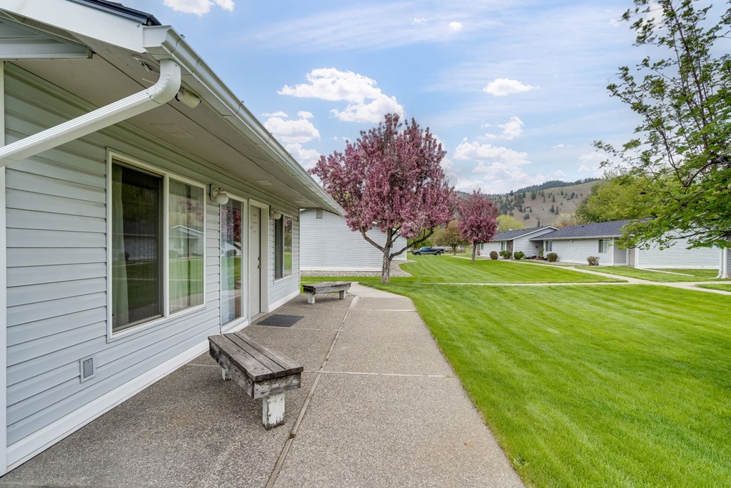 the side of a house with a walkway and a bench