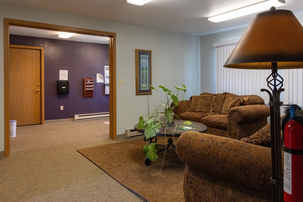 A living room with a brown couch and a fire extinguisher.