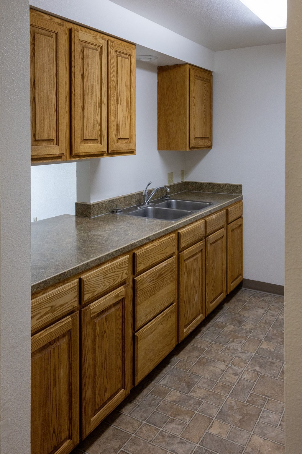 A kitchen with wooden cabinets and a tiled floor.