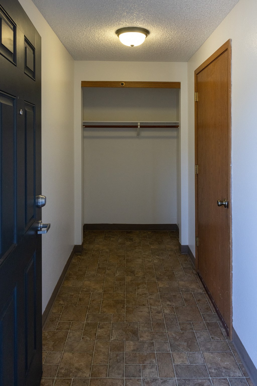 A hallway with a tiled floor and a light on the ceiling.