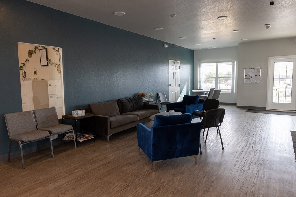 A living room with a grey couch, a blue couch, and a brown chair.