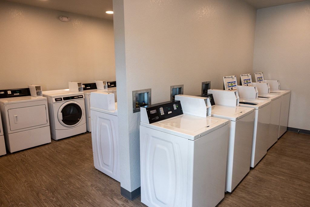 A row of white front load washing machines in a laundromat.